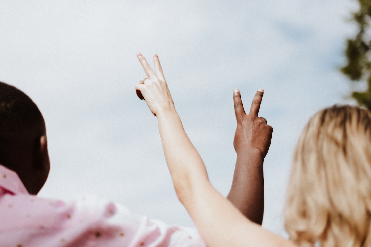 Two people holding up their arm and displaying the peace symbol.